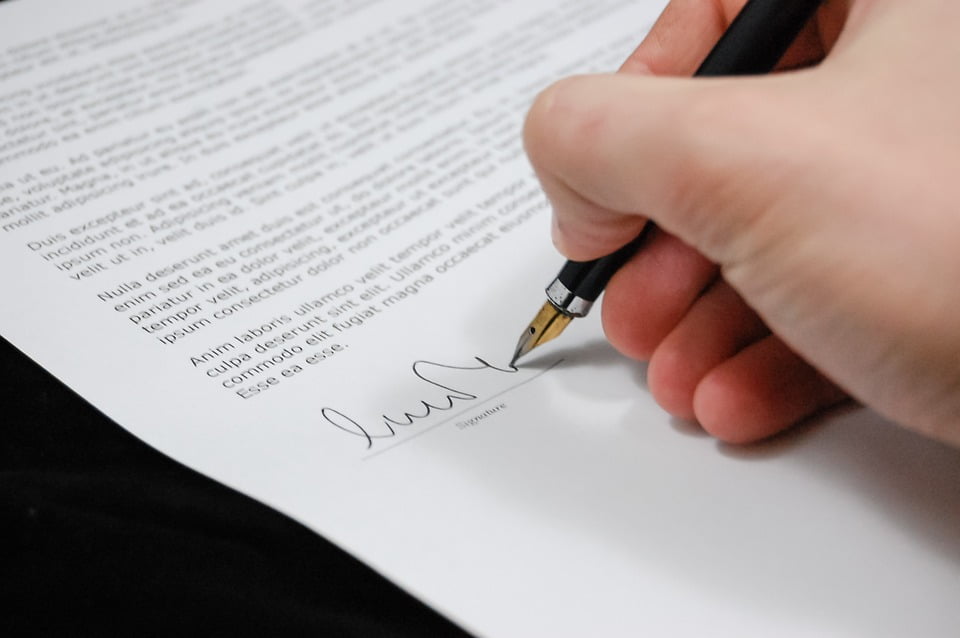Ręka trzymająca pióro i podpisująca dokument